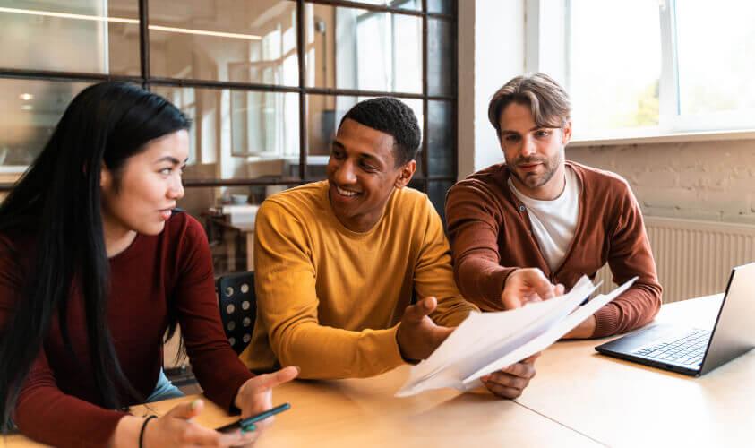 a group of people sitting at a table looking at papers